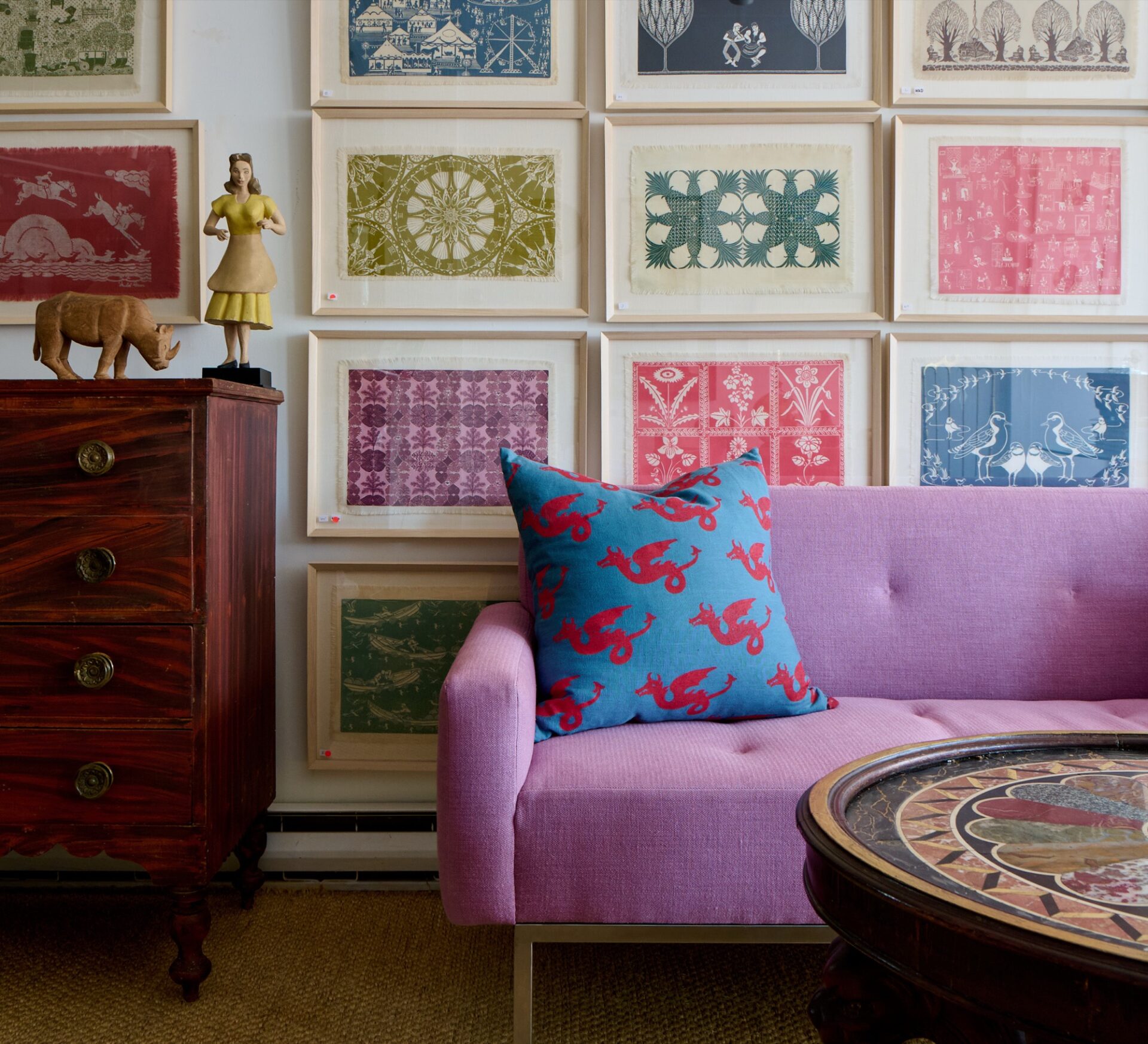 Lavender sofa beneath a wall of framed textile prints styled by Andrew Spindler Antiques & Design