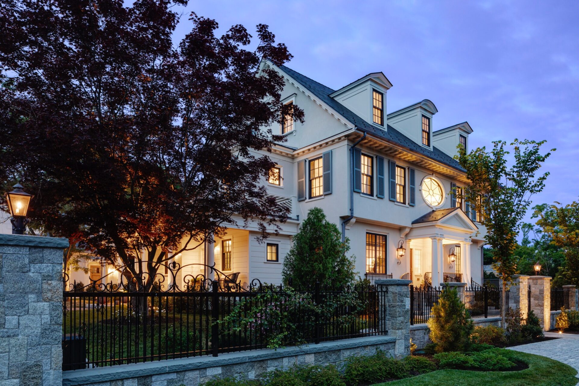 Traditional shingle-and-clapboard home at dusk designed by Carpenter & MacNeille