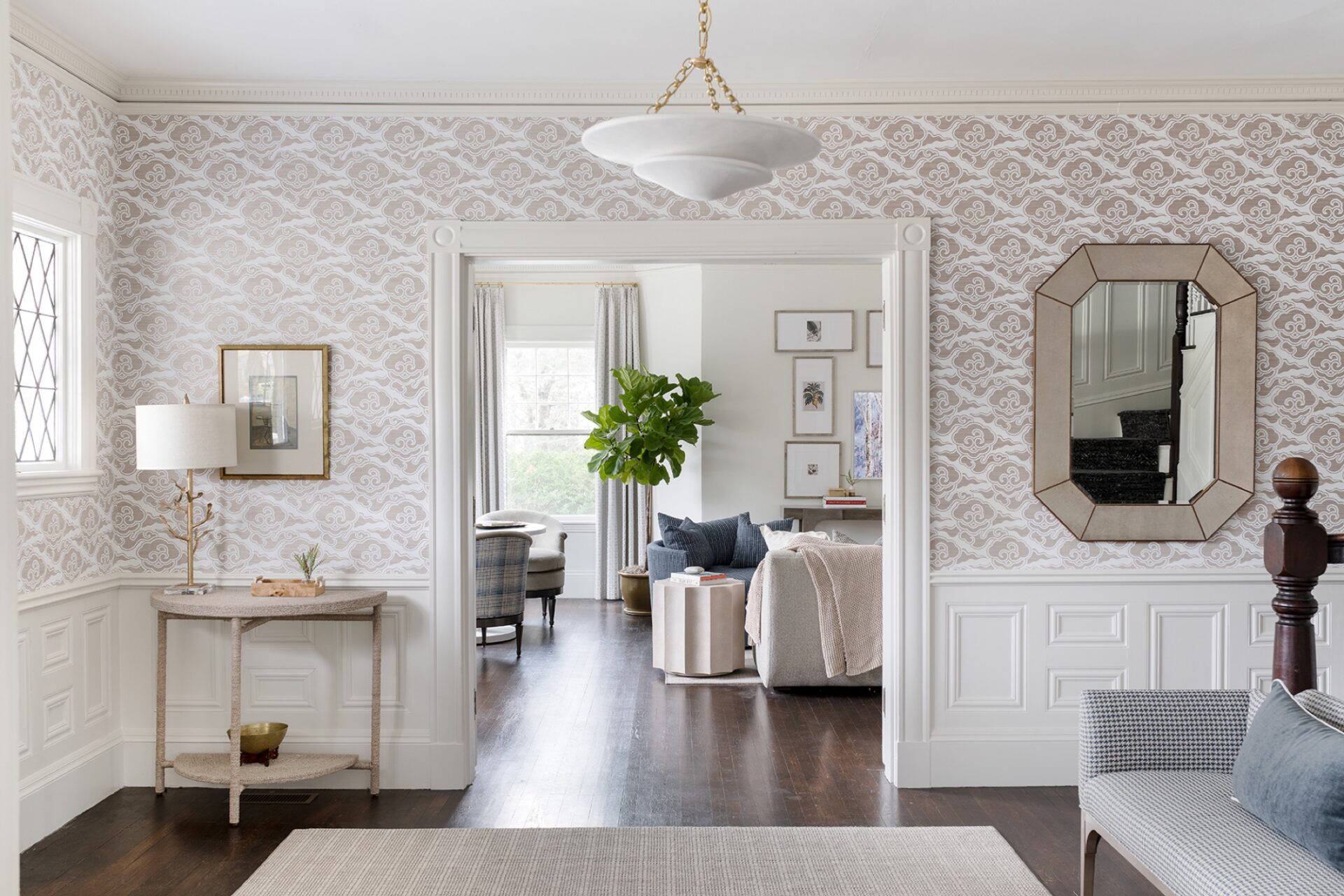Front hall with patterned wallpaper, wainscoting, and an octagonal mirror by Justine Sterling Design