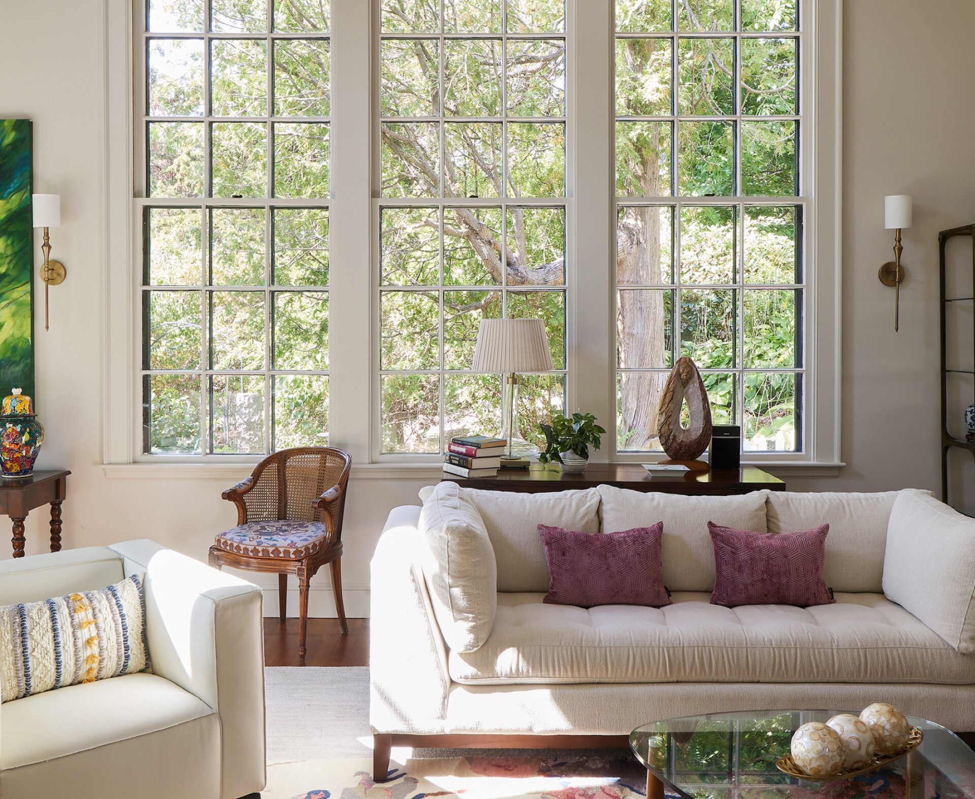 Living room with tall multipane windows and a cream sofa in a home by Olson Lewis + Architects