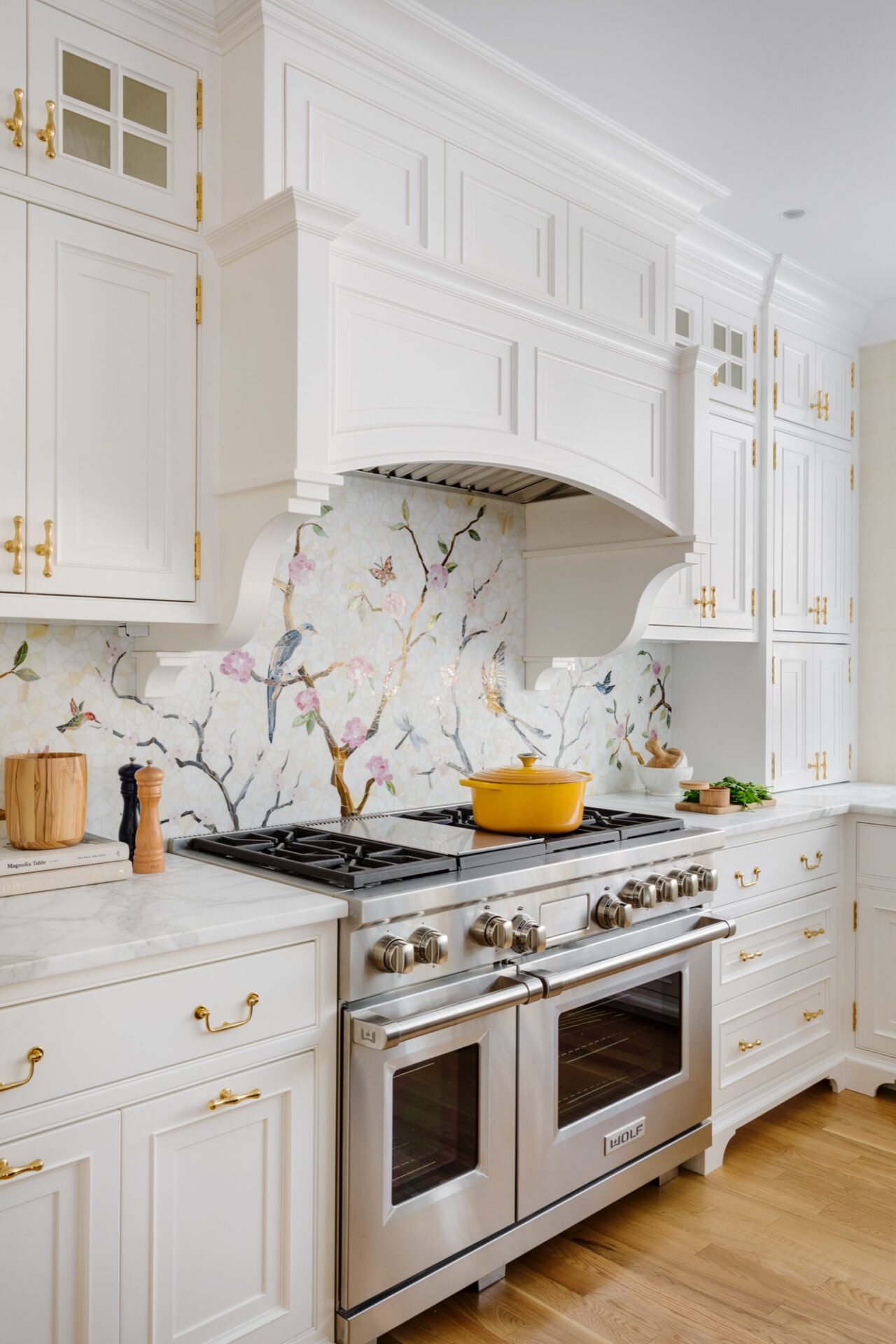 White kitchen with a hand-painted floral backsplash and gold hardware by Platt Cabinetry