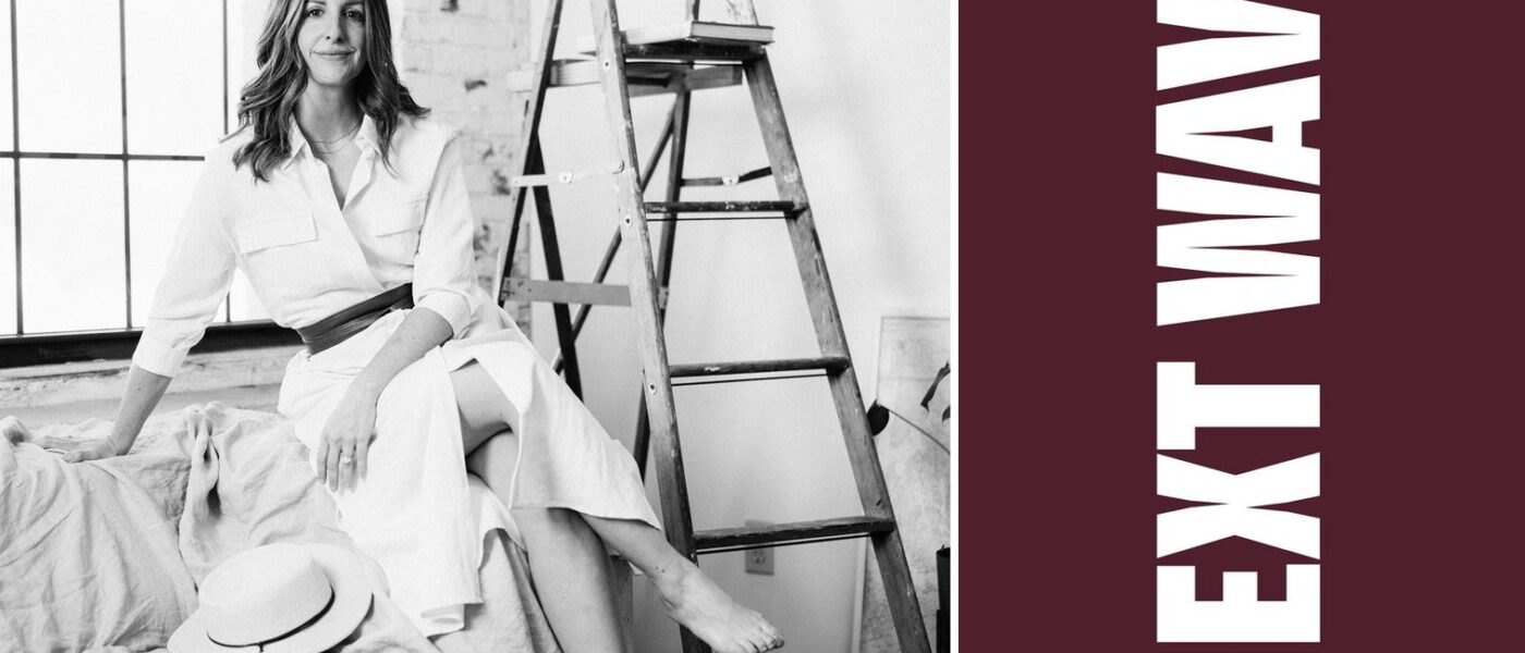 Kelsy Stromski sits near a ladder and tall windows in a black-and-white portrait beside vertical Next Wave lettering on maroon.