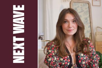 Ocean Lilly Otte wears a floral dress in her boutique beside vertical Next Wave lettering on maroon.