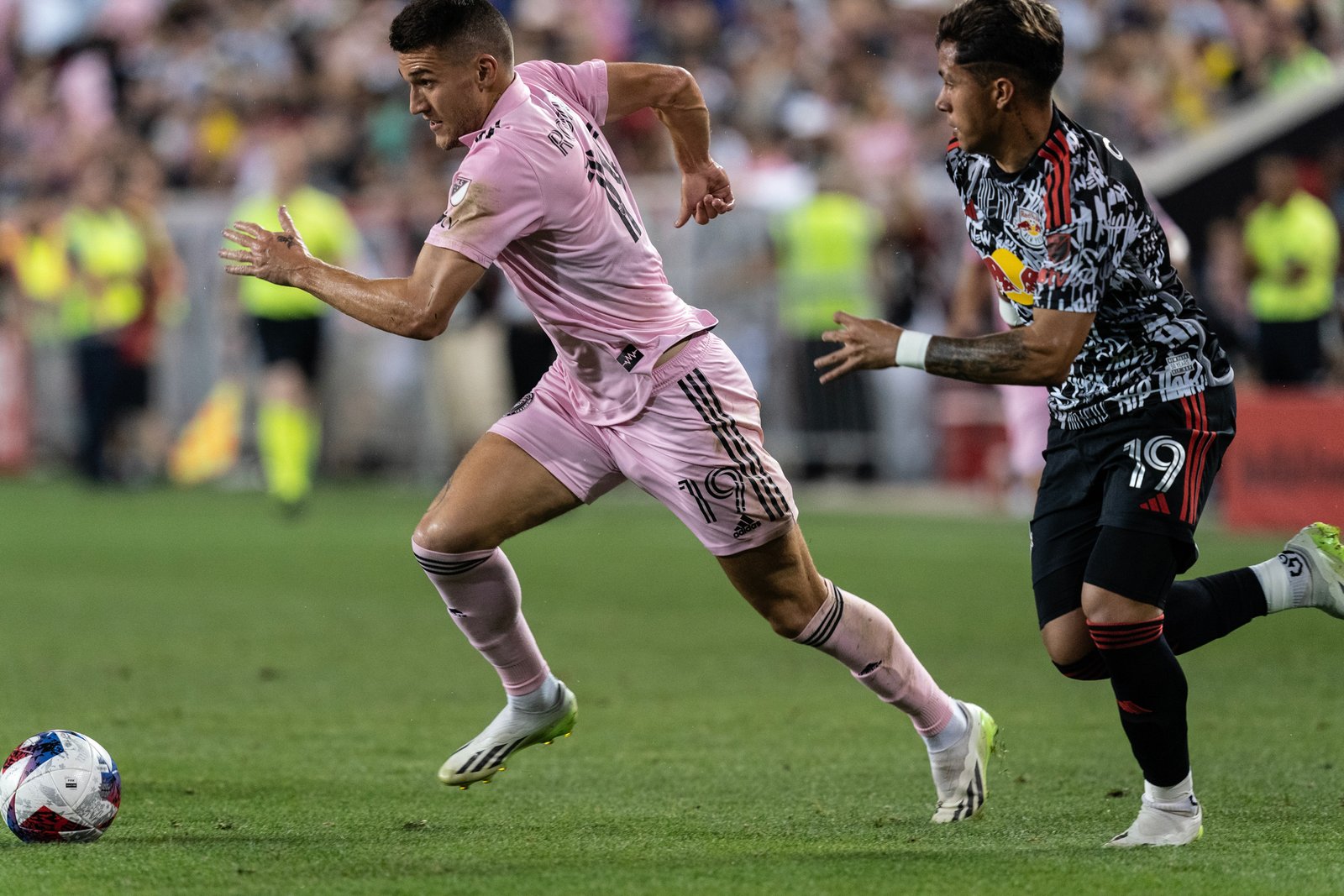 Robbie Robinson in a pink Inter Miami kit runs with the ball during a soccer match.