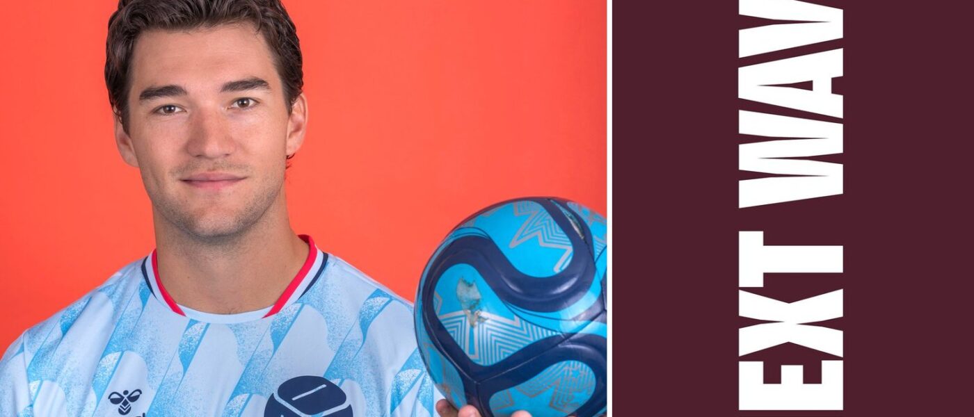 Robbie Robinson holds a soccer ball against an orange background beside vertical Next Wave lettering on maroon.