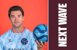 Robbie Robinson holds a soccer ball against an orange background beside vertical Next Wave lettering on maroon.