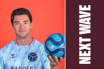 Robbie Robinson holds a soccer ball against an orange background beside vertical Next Wave lettering on maroon.