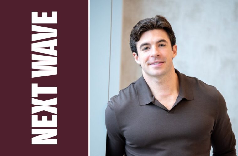 Sal Lupoli Jr. stands with his hands in his pockets beside vertical Next Wave lettering on maroon.