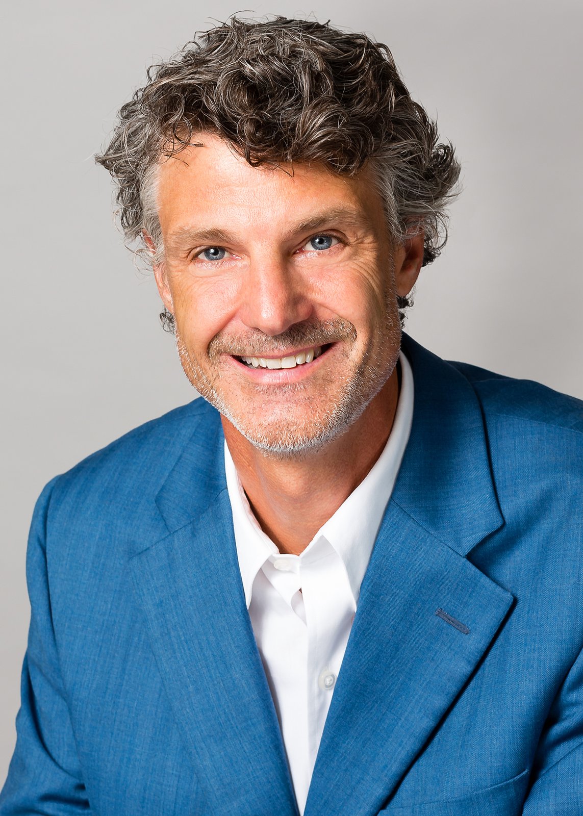 Stratton Lloyd smiles in a blue jacket and white shirt.